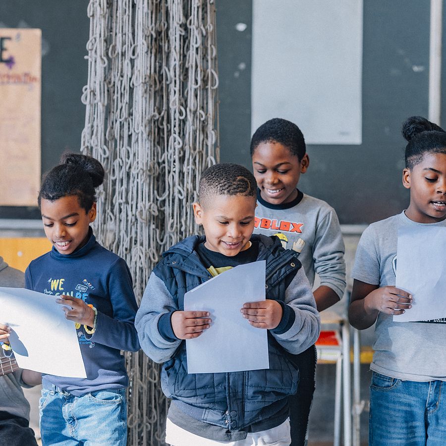 Niños cantando con sus hojas de letra en el taller de música