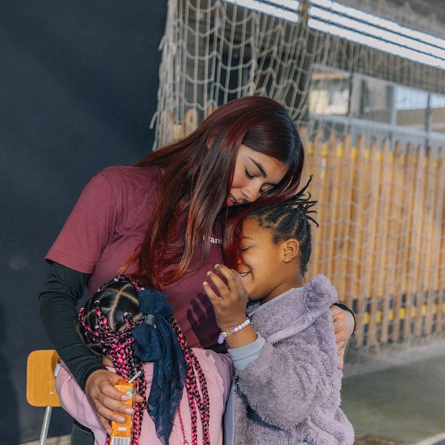 Monitora abrazando a una niña de las colonias