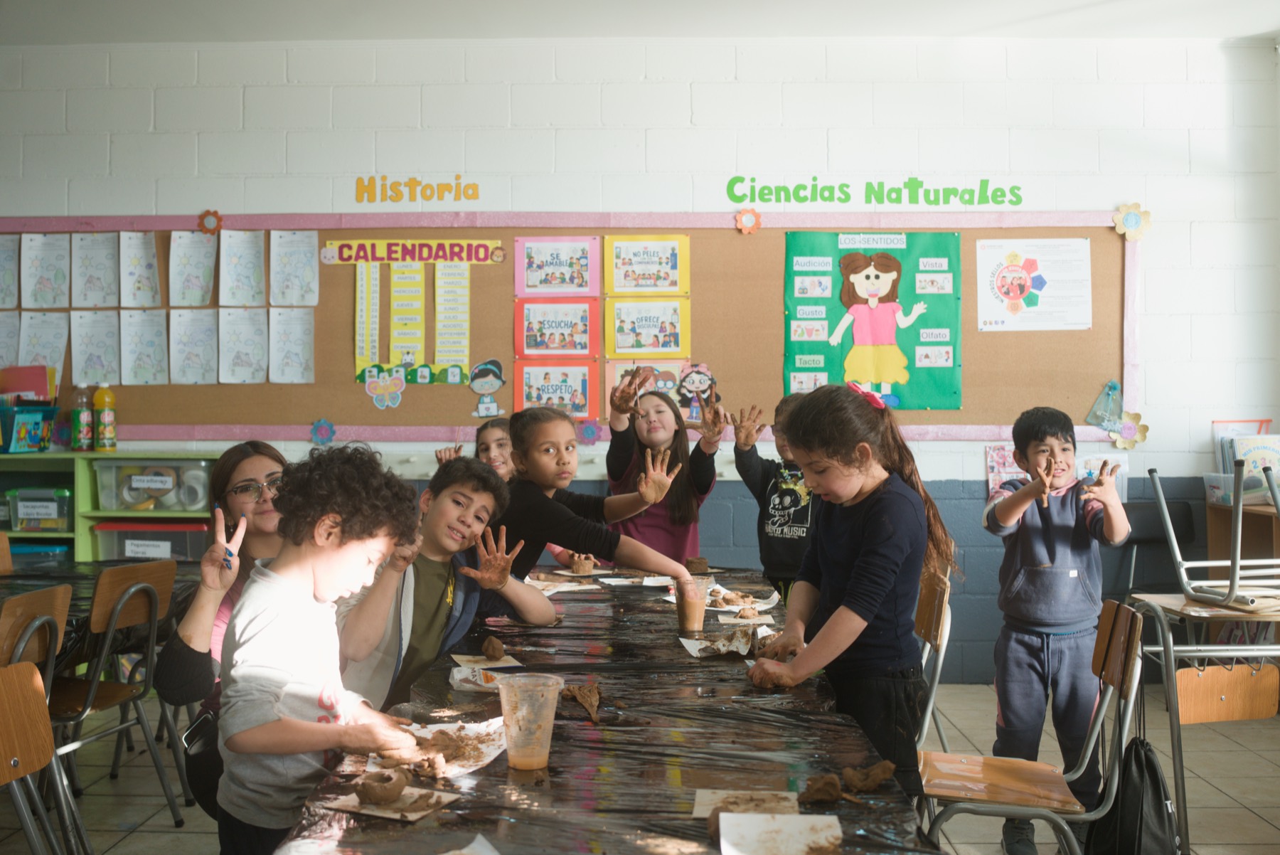 Niñas y niños con las manos llenas de greda en el taller de arte
