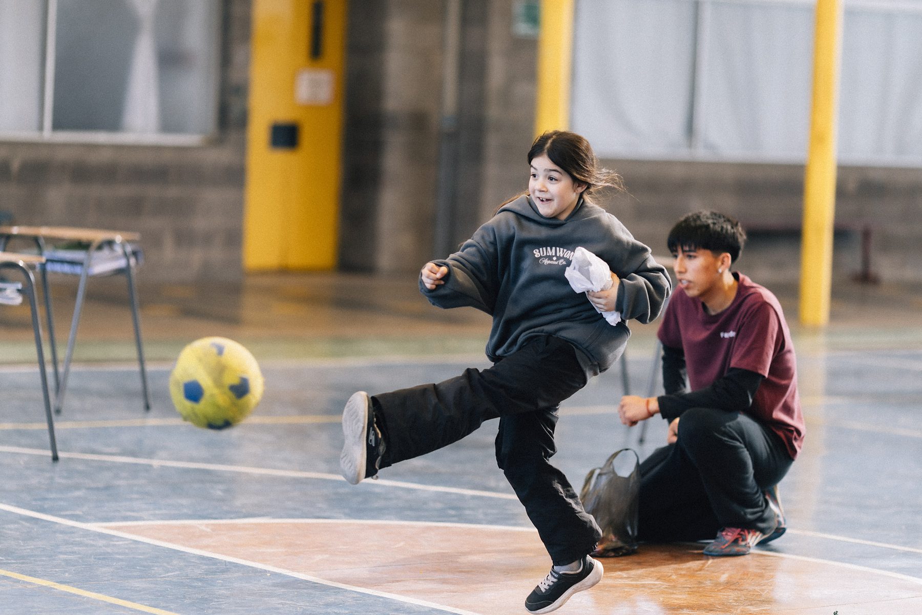 Taller de deporte: una niña patea la pelota en el gimnasio